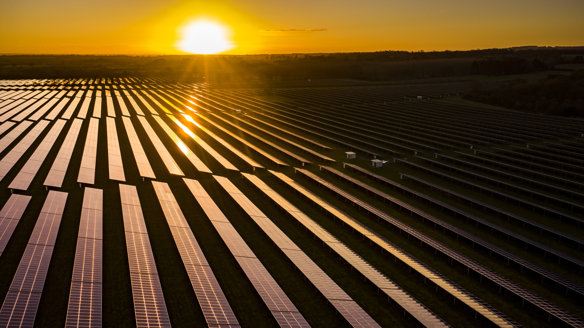Aerial looking over a modern solar farm at sunrise in the English countryside