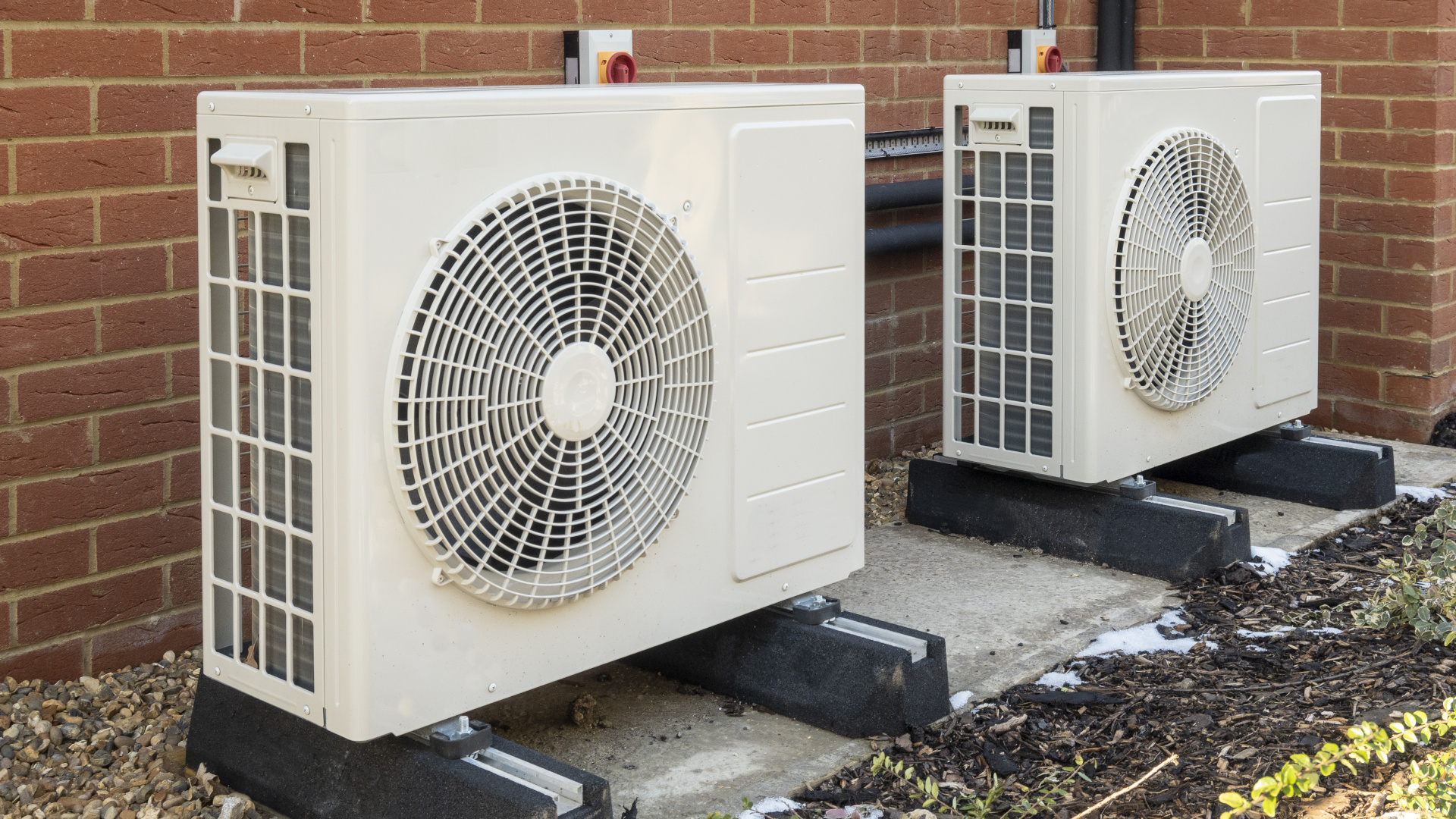 Two air source heat pumps installed on the exterior of a modern house