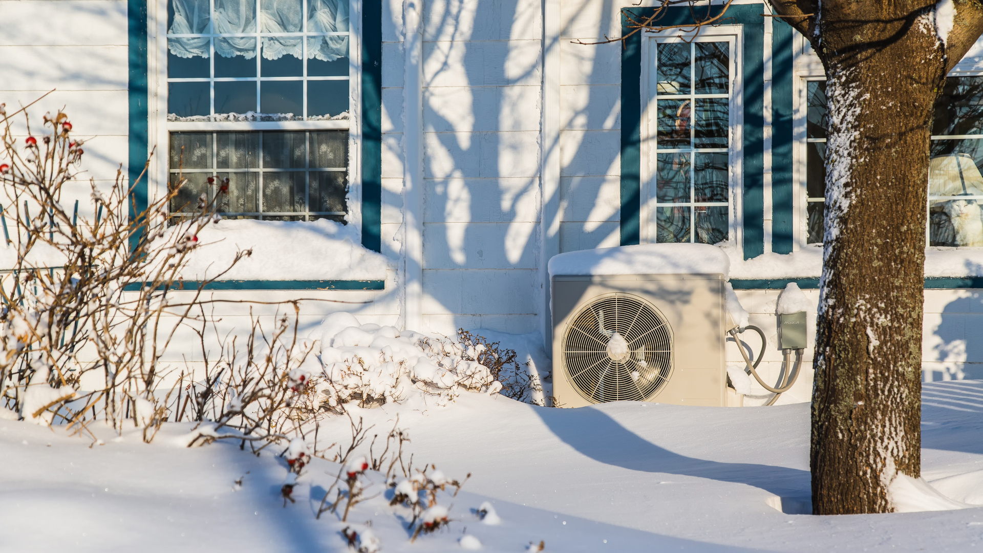 Heat pump unit on the side of a home in winter.