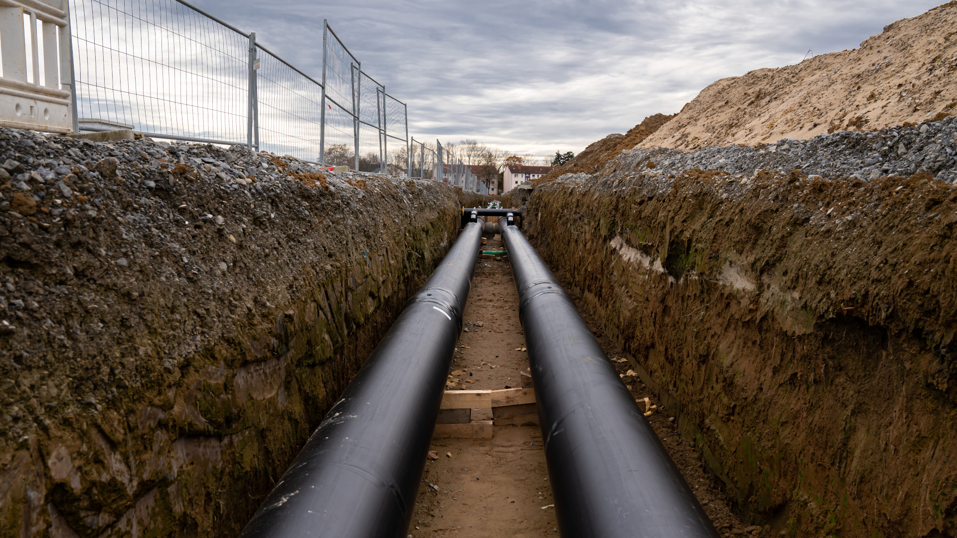 Two large metal pipes with a plastic sheath laid in a trench. Modern pipeline for supplying hot water and heating to a residential area